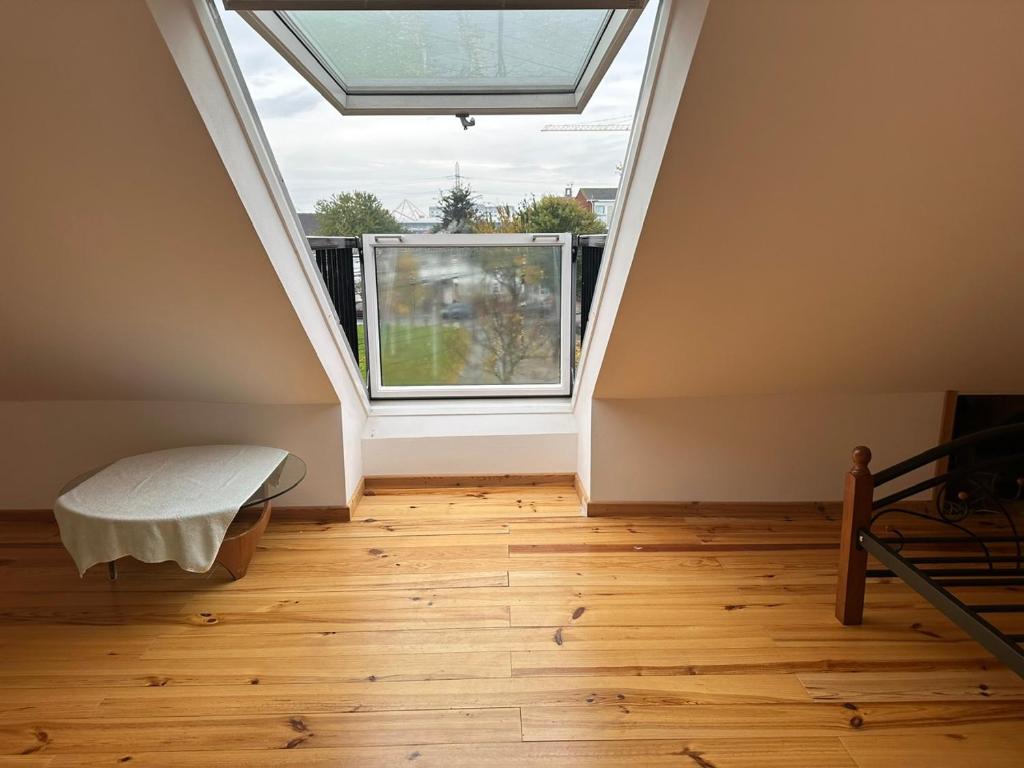 an attic room with a window and wooden floors at Tran Homestay in London