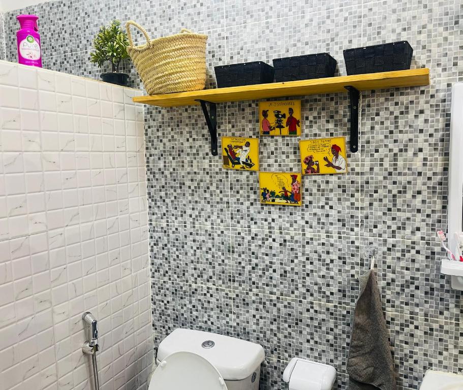 a bathroom with a toilet and a shelf on a wall at Villa diam la paix in Guediawaye