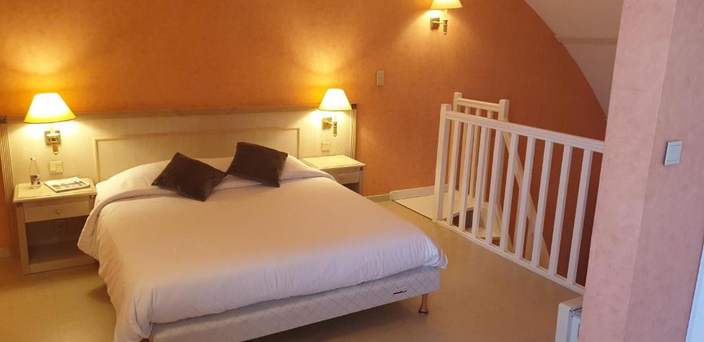 a bedroom with a white bed and a staircase at Logis L'Auberge Bourbonnaise in Saint-Yorre