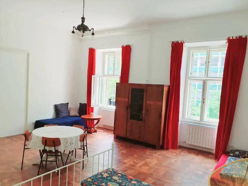 ein Wohnzimmer mit einem Tisch und roten Vorhängen in der Unterkunft Suja Nuja in Ljubljana