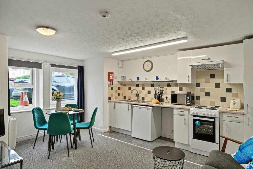 a kitchen with white cabinets and a table and chairs at Finest Retreats - Atherfield Apartments No 4 - Lawn Side in Paignton