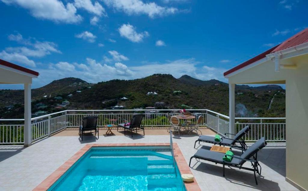 un patio con piscina, sillas y mesa en Saint Barth Villa 3, en Saint-Jean