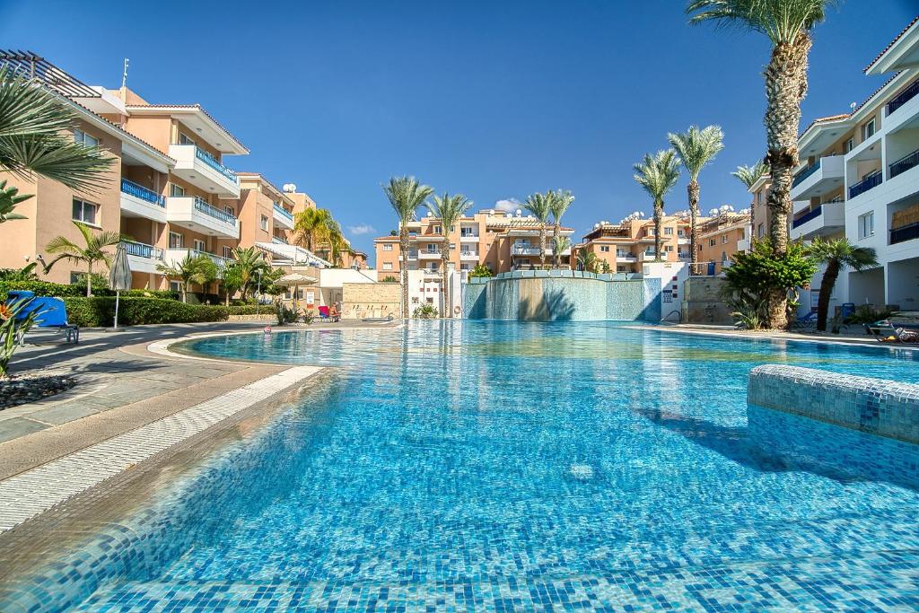 een zwembad in een resort met palmbomen en gebouwen bij Iris Village Block 12-105 in Paphos City