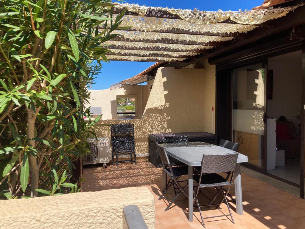 une terrasse avec une table et des chaises dans une maison dans l'établissement Village naturiste - Port-Vénus villa n°45 avec piscine, au Cap d'Agde