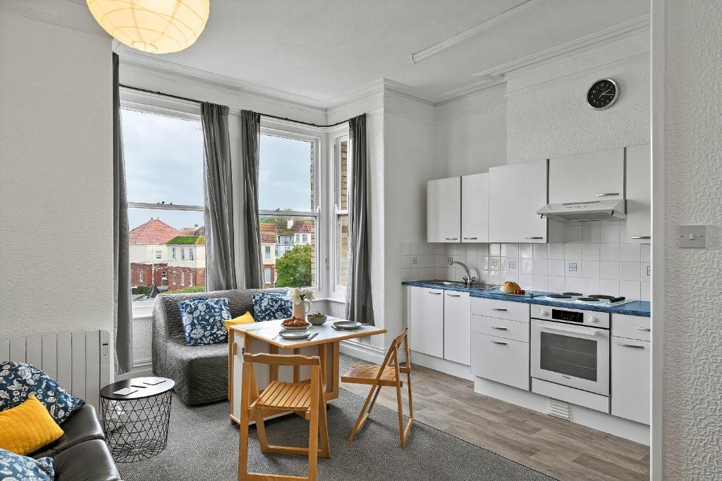 a kitchen with a table and a living room at Finest Retreats - Atherfield Apartments No 5 - Sea Views in Paignton