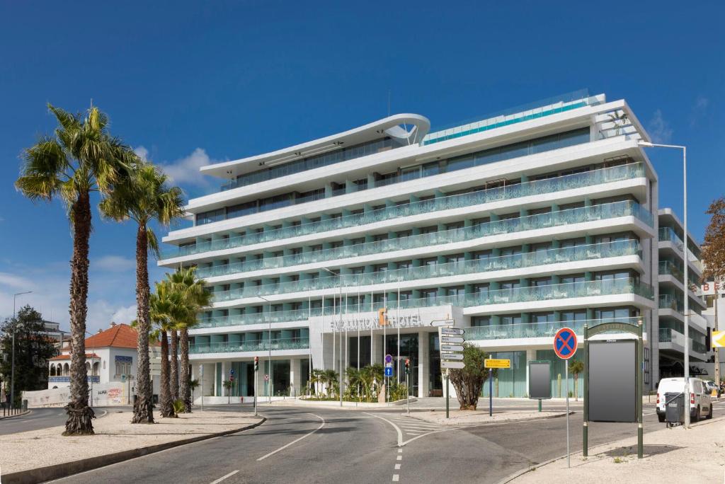 a large white building with palm trees in front of it at EVOLUTION Cascais-Estoril Hotel in Estoril