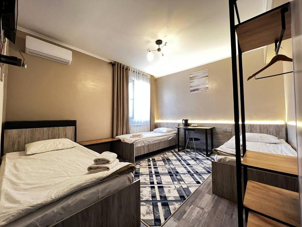 a bedroom with two beds and a desk in it at Ave hotel in Osh