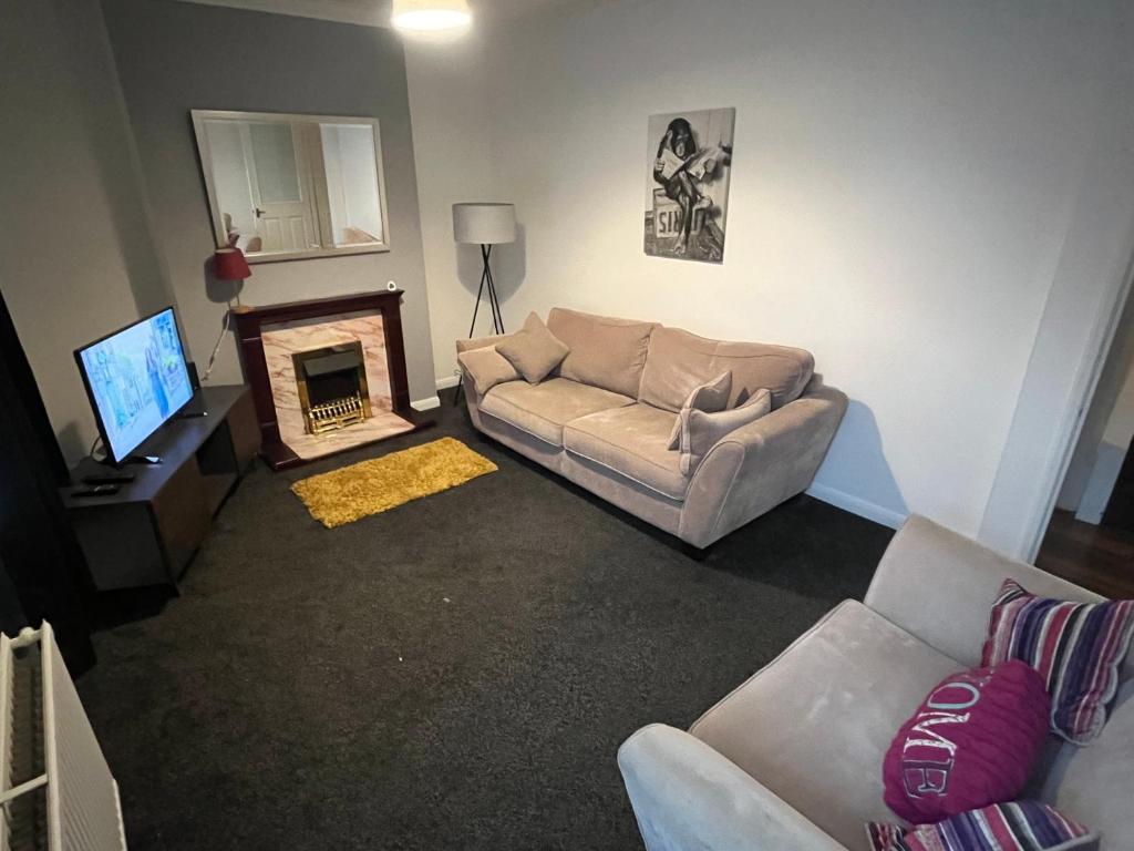 a living room with a couch and a fireplace at Super Value Three Bedroom House in Hull