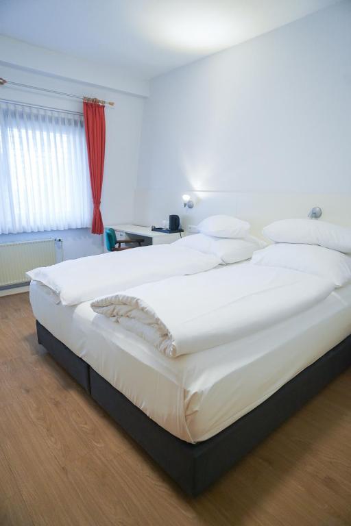 a large white bed in a room with a red curtain at AP Hotel Mannheim Viernheim am Kapellenberg in Viernheim