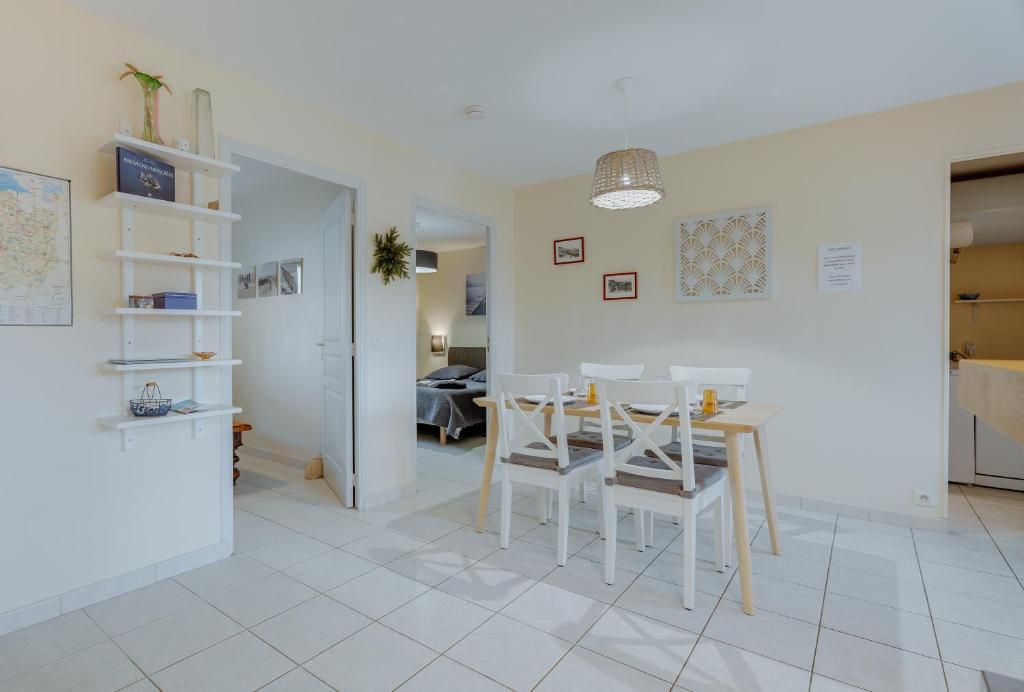 una cucina e una sala da pranzo con tavolo e sedie di Grain de sable a Saint-Benoît-des-Ondes