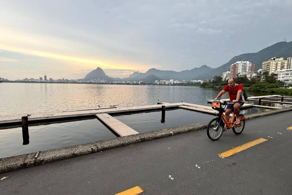 Un uomo che va in bicicletta su una strada vicino a un corpo d'acqua di Estilo de vida carioca a Rio de Janeiro