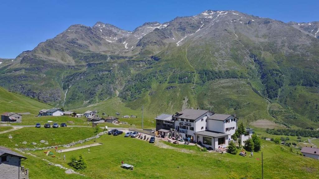ein Haus auf einem Hügel mit einem Berg im Hintergrund in der Unterkunft Rifugio "Mai Tardi" in Madesimo