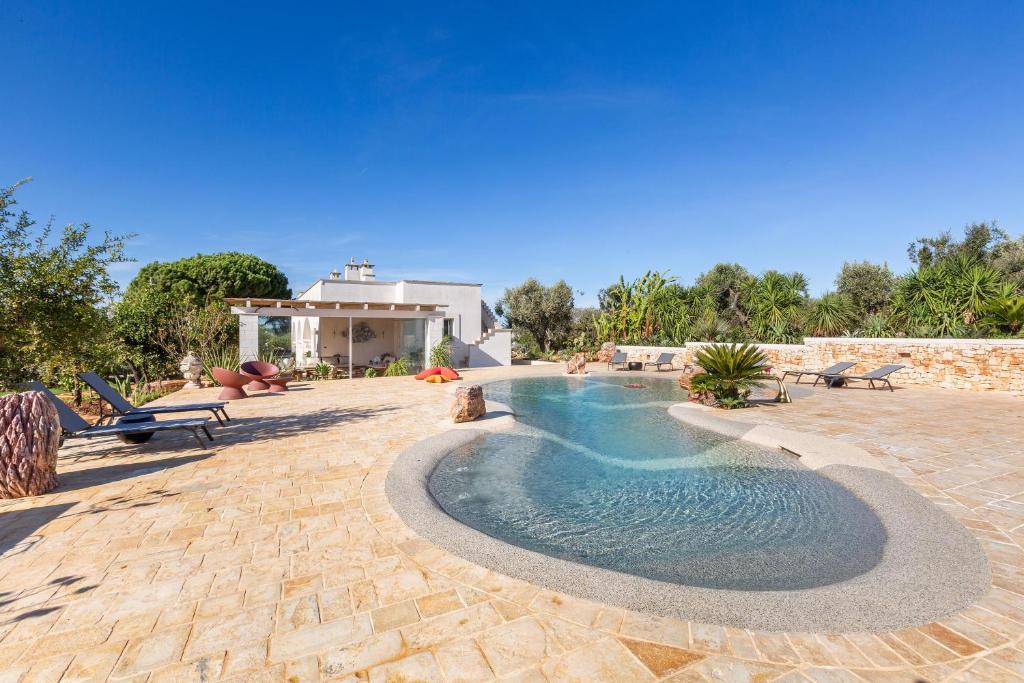 une piscine avec bancs et une maison dans l'établissement Ca` della Roccia by Perle di Puglia, à Ostuni