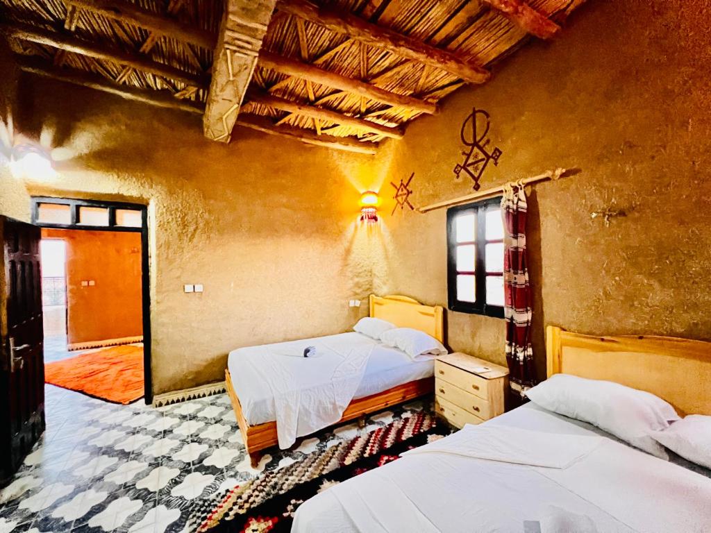 una camera da letto con due letti in una stanza di Hotel Camping Les Roses Des Dunes & Piscine a Merzouga