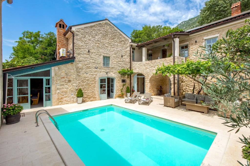 an outdoor swimming pool in front of a stone house at Villa Ivka in Tribalj