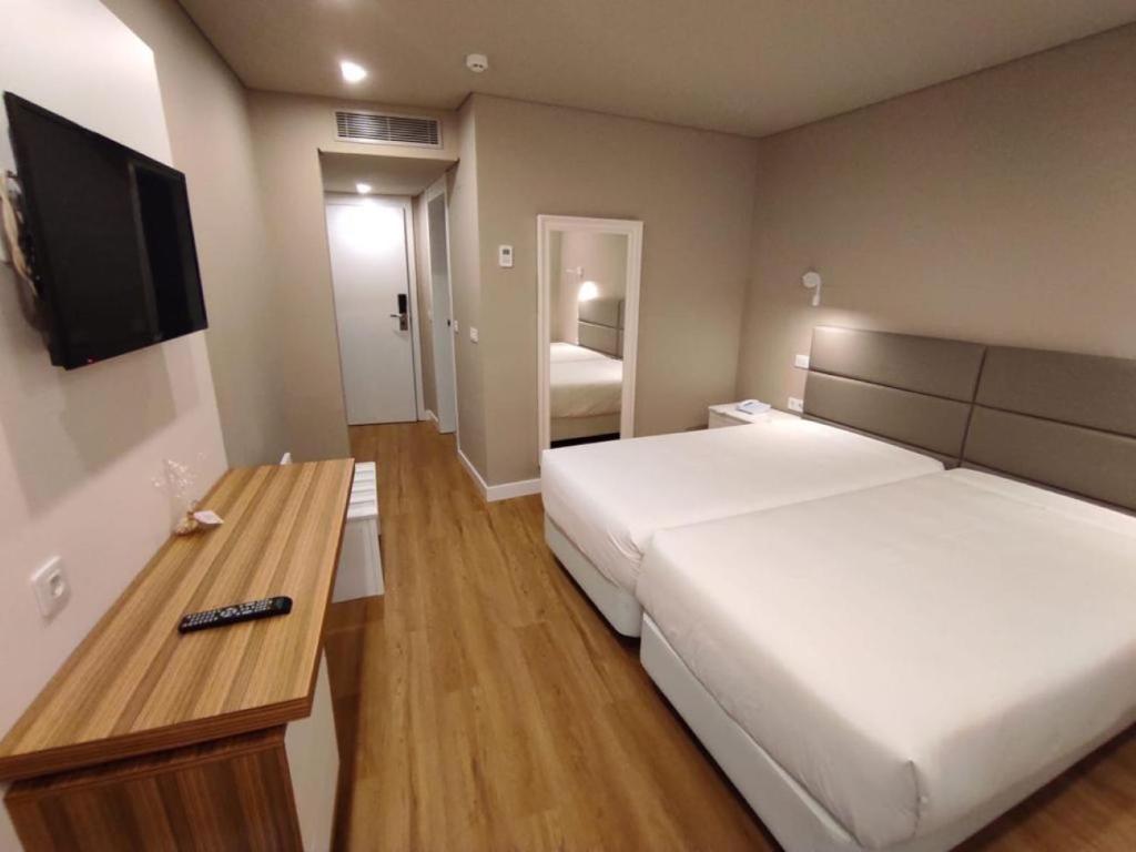 Cette chambre comprend deux lits et une télévision. dans l'établissement Hotel Cristal Caldas, à Caldas da Rainha
