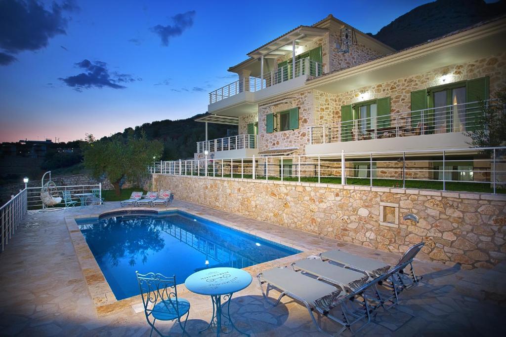 a villa with a swimming pool in front of a building at Petra & Thalassa in Plataria