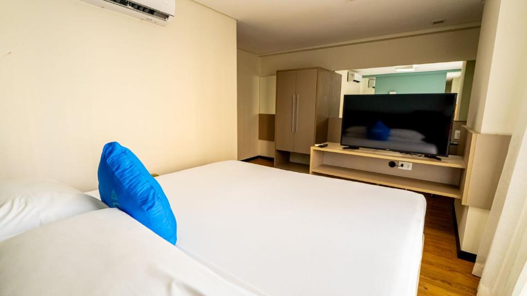 a hotel room with two beds and a flat screen tv at Roomo Praia de Boa Viagem Residencial in Recife