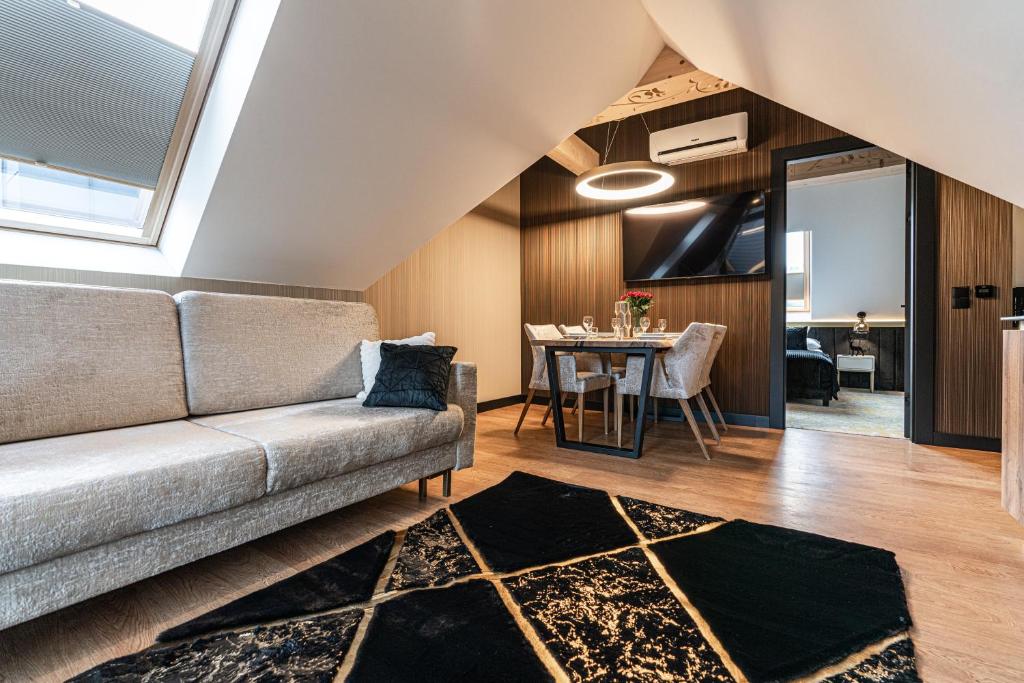 Bright loft living area with gray sofa, dining table, skylight and black geometric rug.