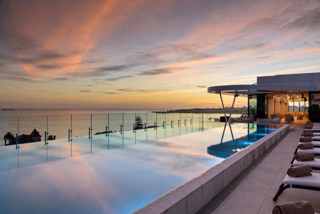 ein Pool auf dem Dach eines Gebäudes mit Meerblick in der Unterkunft EVOLUTION Cascais-Estoril Hotel in Estoril