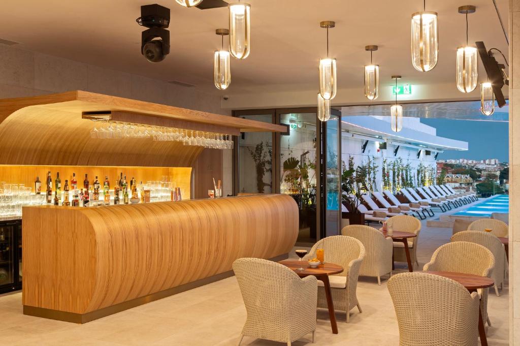 a restaurant with a bar with chairs and a pool at EVOLUTION Cascais-Estoril Hotel in Estoril