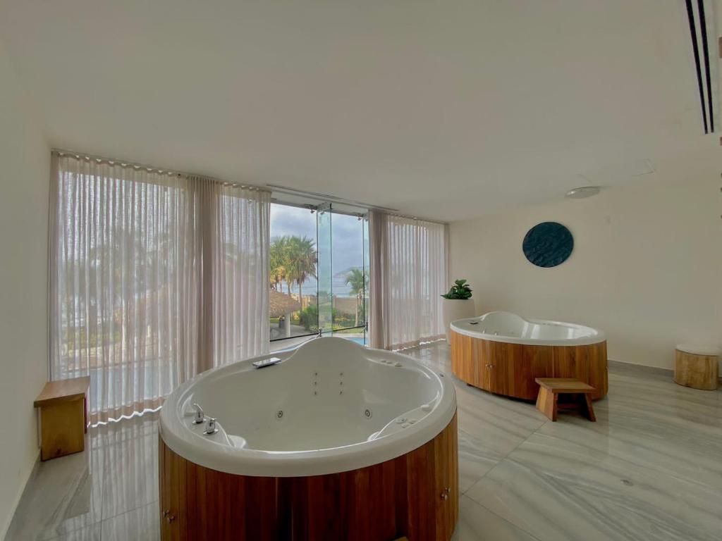 a large bathroom with two tubs and a large window at Apartment In Camino Al Mar with Amazing View of the Ocean, Beach and Swimming Pool, 2 Rooms in Mazatlán