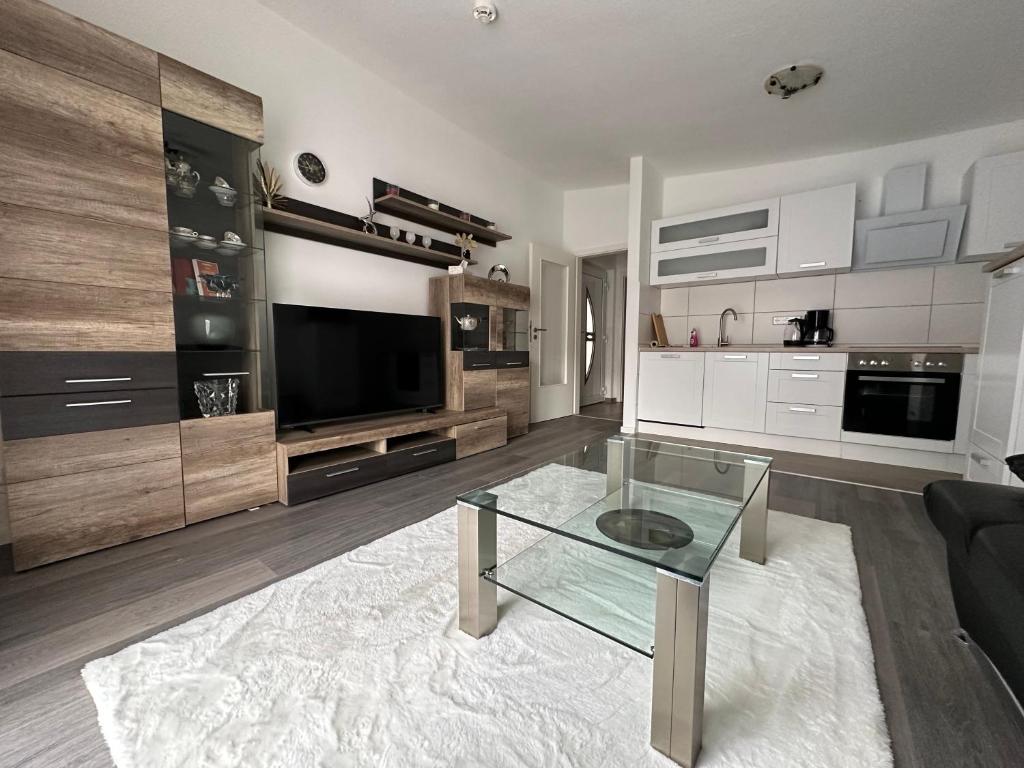 ein Wohnzimmer mit einem Glastisch und einem TV in der Unterkunft Villarina in Dresden