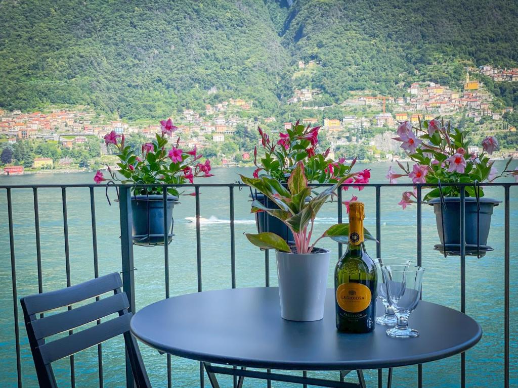 un tavolo con una bottiglia di vino e fiori sul balcone di Balcony On The Lake - Free Parking, Lake view a Laglio