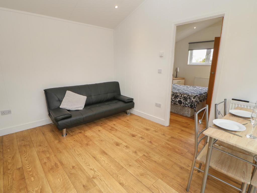 a living room with a black couch and a table at Wensleydale Pod in Yarm