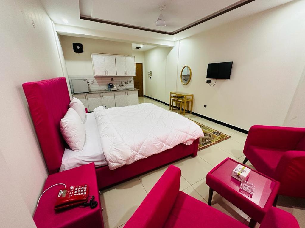 イスラマバードにあるWE hotels Islamabadのベッド付きの部屋、赤い椅子付きのキッチン