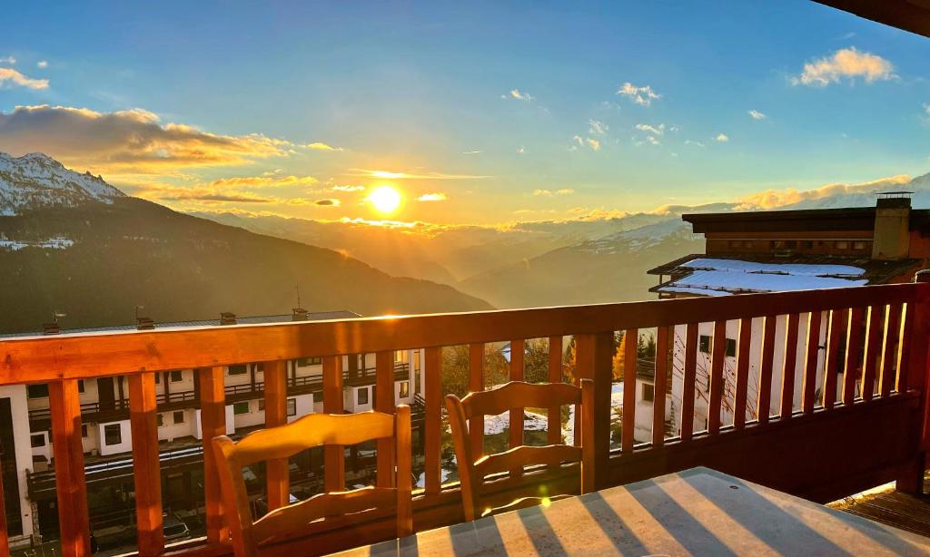 d'un balcon avec une table et des chaises et un coucher de soleil. dans l'établissement Studio cosy Centre station de ski La Rosière 1850 vue magnifique plein Sud, à Montvalezan