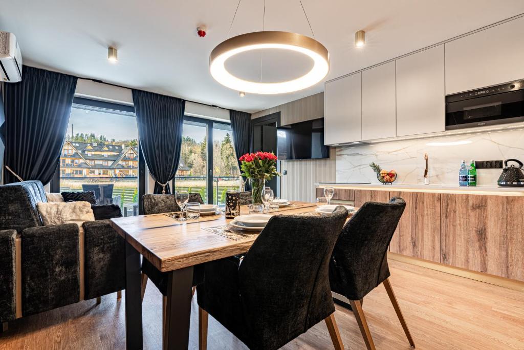 Open-plan dining and kitchen with rustic table, black upholstered chairs and circular pendant light