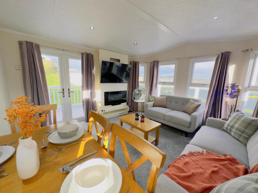 a living room with a table and a dining room at LakeDistrict Caravan by Sleepy in Millom