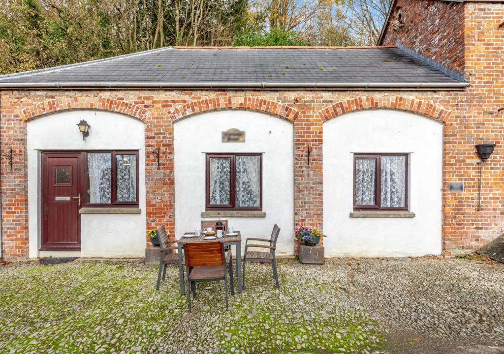 a brick house with a table and chairs in front of it at The Carriage House Upcott House in Barnstaple