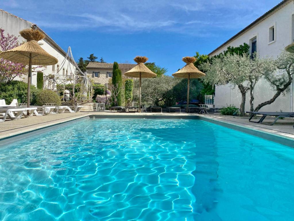 una piscina azul con sombrillas en un patio en Hotel du Soleil et Spa, en Saint-Rémy-de-Provence