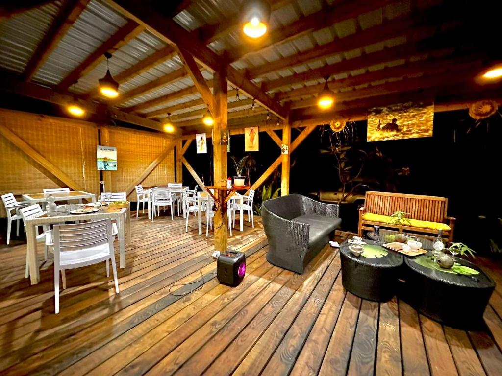 ein Restaurant mit Tischen und Stühlen auf einem Holzboden in der Unterkunft Manomano Lodge in Papara