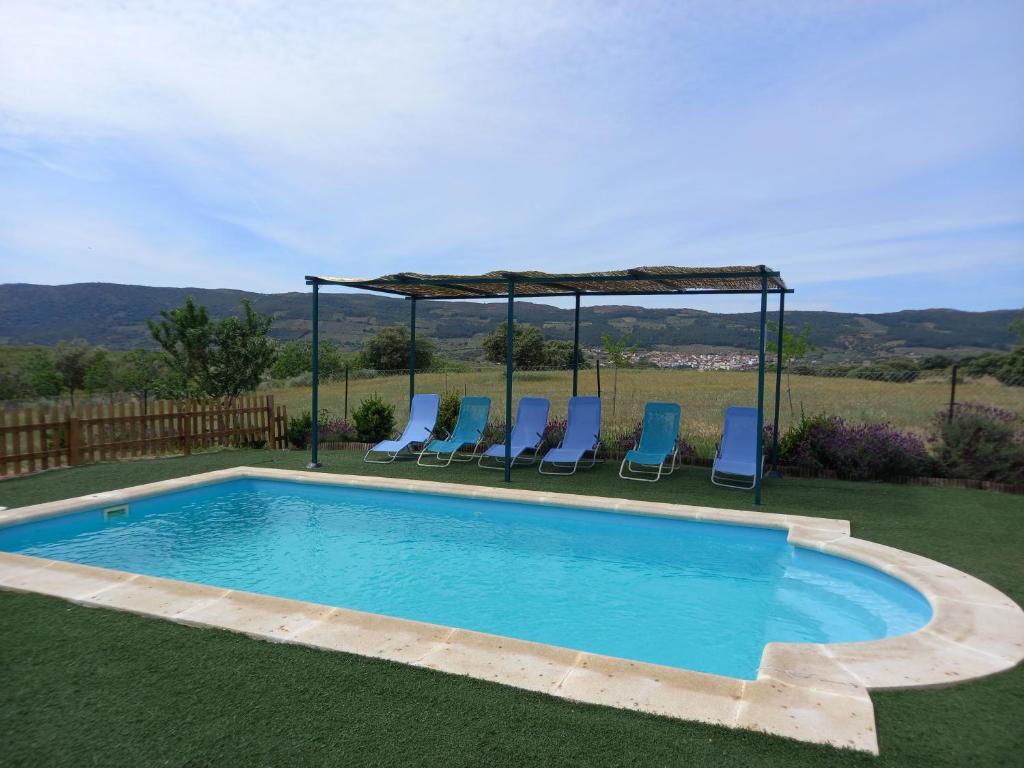 - une piscine avec des chaises et un kiosque dans l'établissement CASA RURAL LA HOJA EL VALLE, à Valdecaballeros