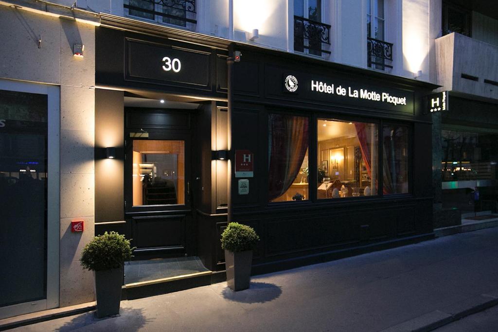 ein Geschäft mit zwei Topfpflanzen vor einem Gebäude in der Unterkunft Hôtel de la Motte Picquet in Paris