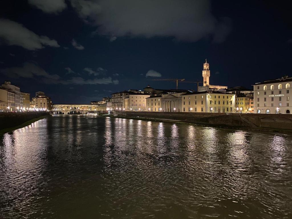 a river with buildings and a city at night at signoria flat 5* centro storico in Florence