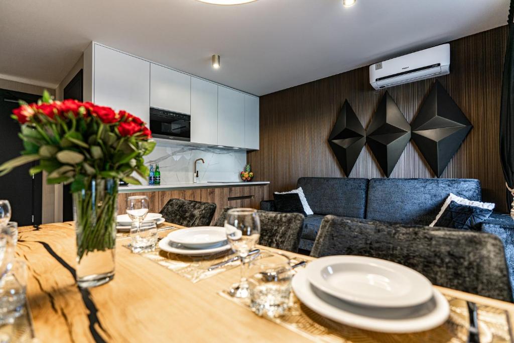 Open-plan dining and kitchen with set wooden table, sofa and geometric wall art.