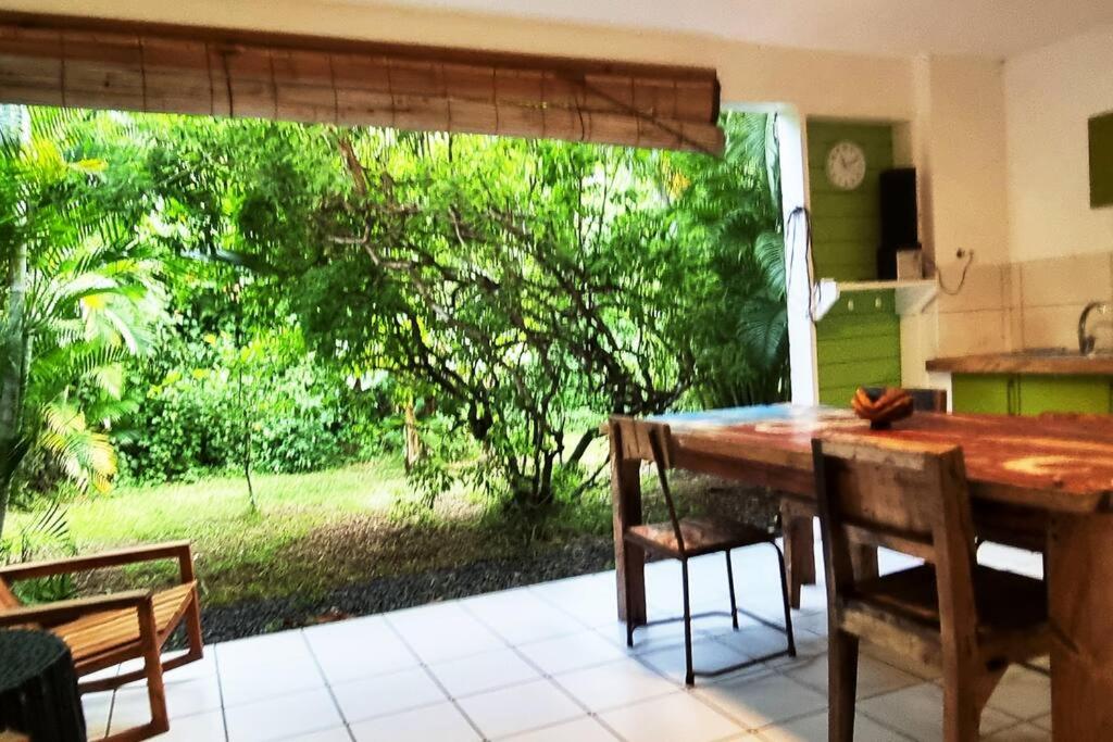 eine Küche mit einem Tisch und Stühlen sowie einem Fenster in der Unterkunft PAPAYE VERTE habitation CALISSA in Bouillante