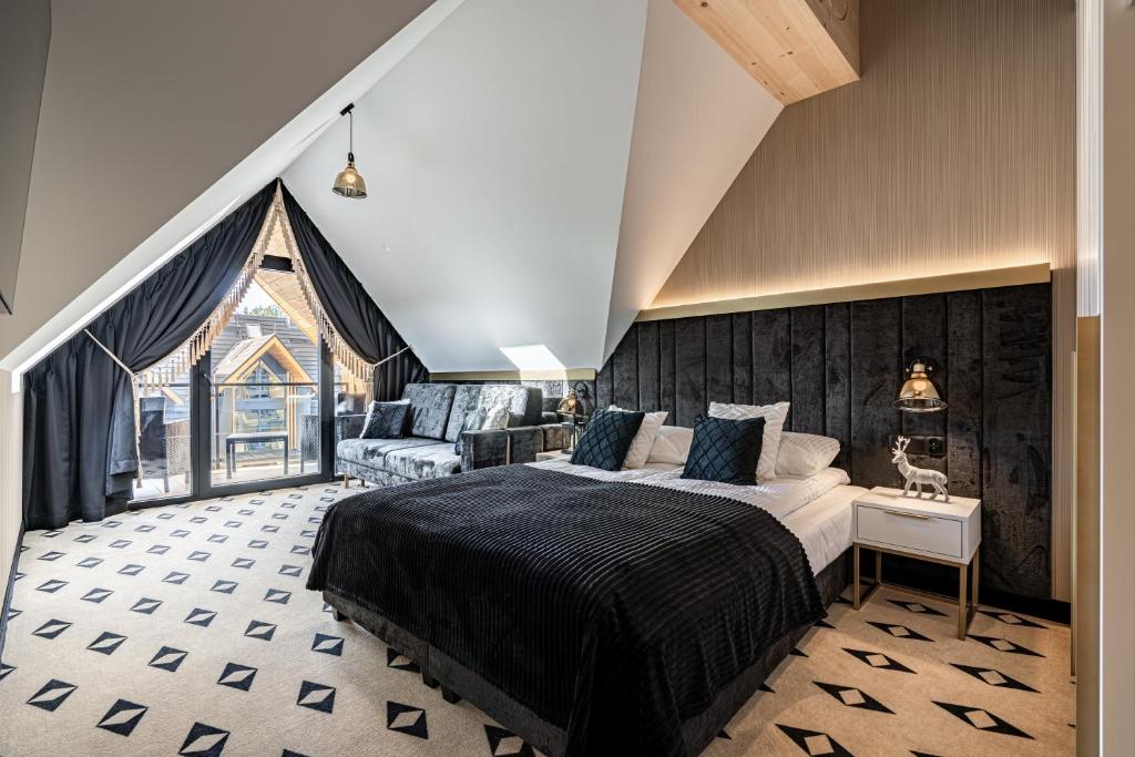 Attic bedroom with king bed, plush black headboard, patterned carpet and balcony doors.