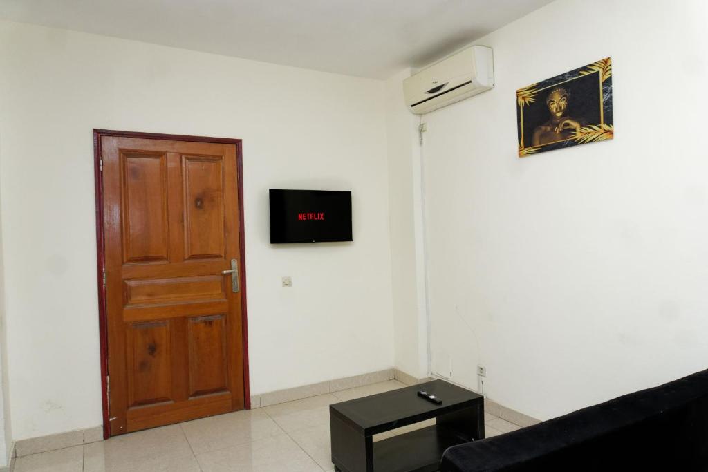 Habitación con puerta y TV en la pared en Résidence Céline, en Libreville