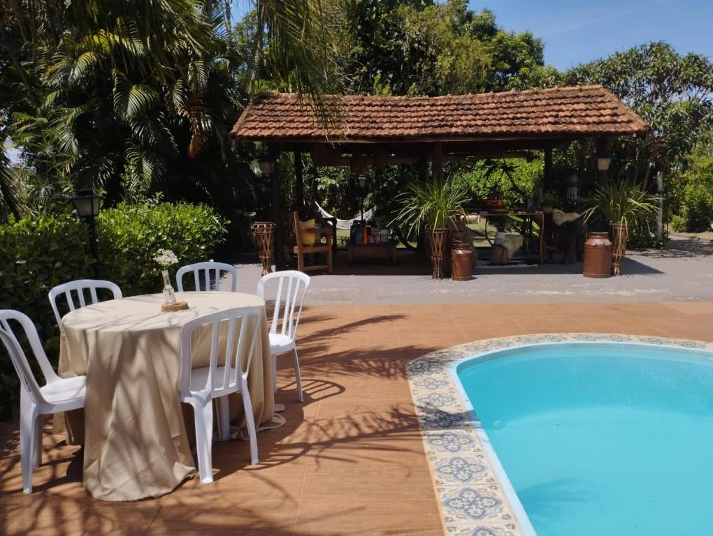 a table and chairs next to a swimming pool at Estância São Sebastião in Cafelândia