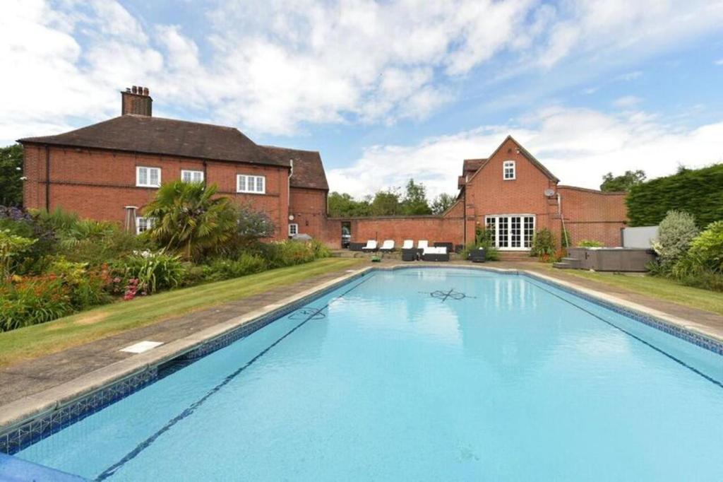 a large swimming pool in front of a brick building at Amazing 100 year old church Rectory in Brentwood