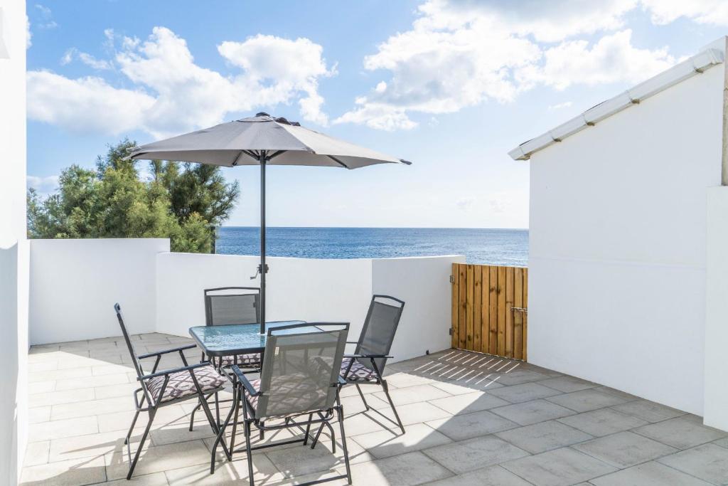 eine Terrasse mit einem Tisch, Stühlen und einem Sonnenschirm in der Unterkunft Forno da Cal Sea House in São Roque