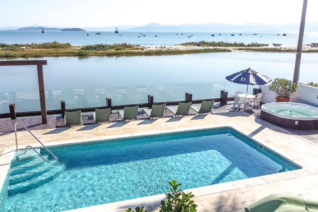 uma piscina com cadeiras e vista para o oceano em Costa Norte Ponta das Canas Hotel em Florianópolis