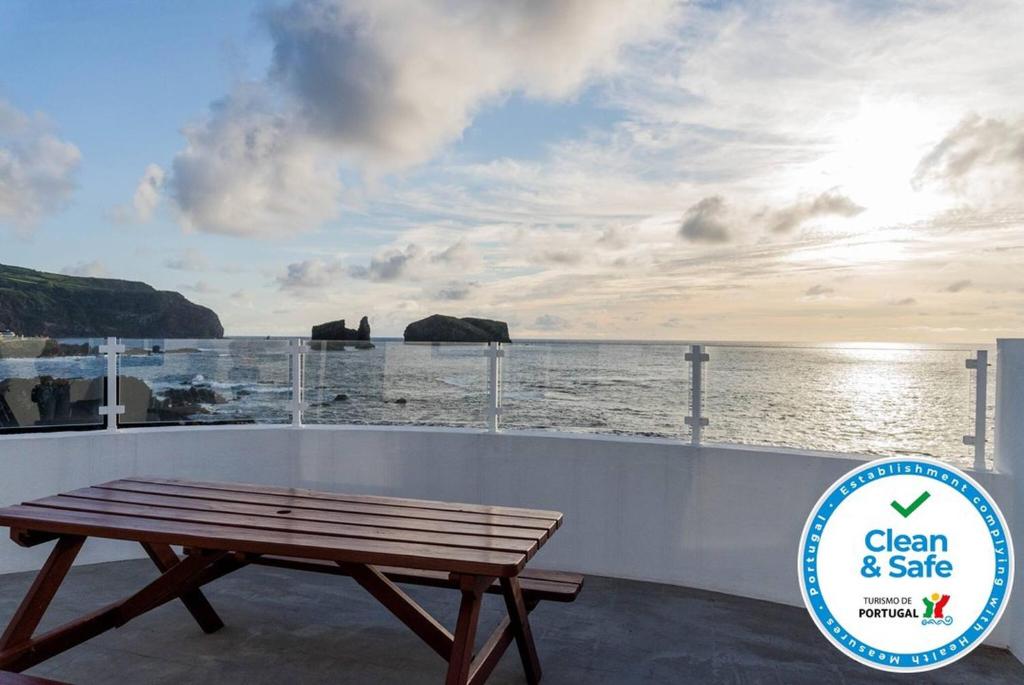 a wooden bench sitting on a balcony overlooking the ocean at Casa dos Mosteiros 1740/AL in Mosteiros