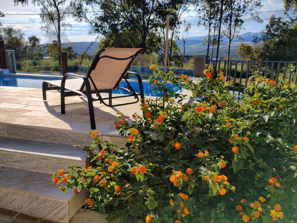 krzesło siedzące obok krzaka z pomarańczowymi kwiatami w obiekcie Pousada Ribeirinha w mieście São José da Barra