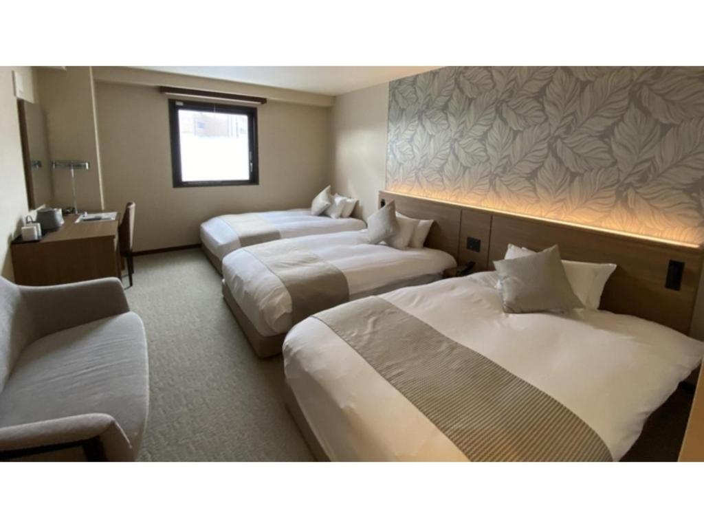 Habitación de hotel con 3 camas y sofá en Kutsurogi no Yado Juraku - Vacation STAY 03512v en Tobe